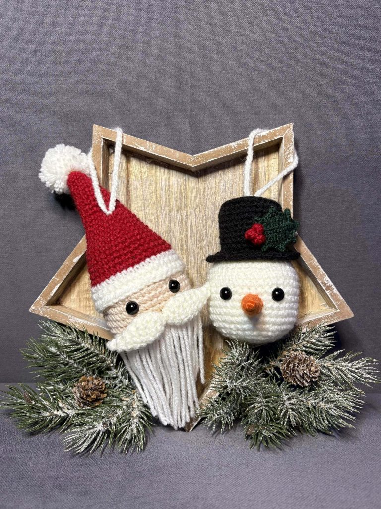 Two crocheted ornaments, one Santa and one snowman, are displayed in front of a wooden star frame with pine branches and pinecones at the bottom—a festive scene ideal for showcasing your favorite crochet pumpkin pattern.