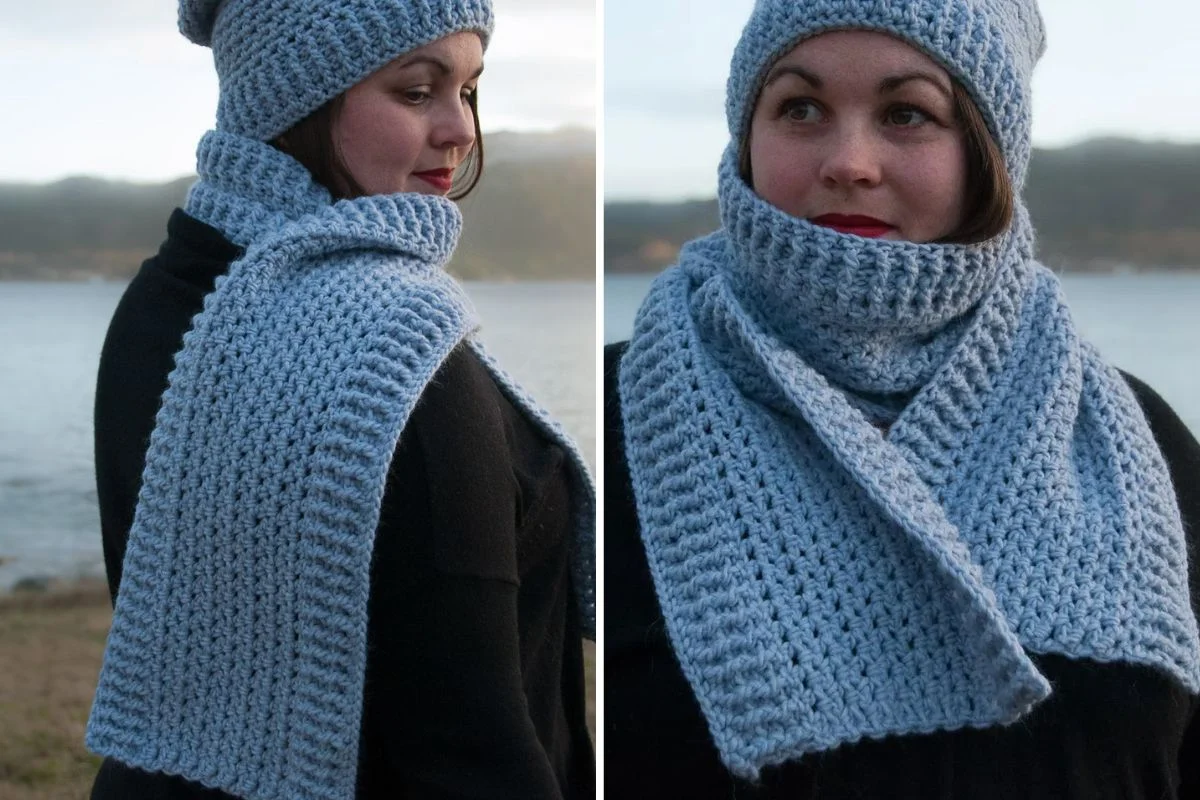 Woman wearing a matching light blue crocheted winter seashore scarf and hat, standing outdoors near water, dressed in a black coat.