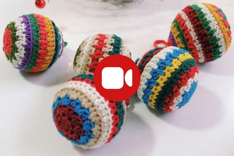 Five colorful crocheted Christmas ornaments are arranged on a white surface.