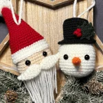 Crocheted Santa Claus and snowman ornaments hang on a wooden star frame decorated with pine branches, pine cones, and a charming pumpkin crochet pattern for added festive flair.