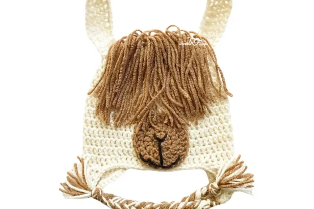 A crocheted hat resembling a llama's face, with brown yarn for the nose and mane, cream-colored base, and braided ties—perfect to pair with your favorite crocheted snowman accessories for a whimsical winter look.