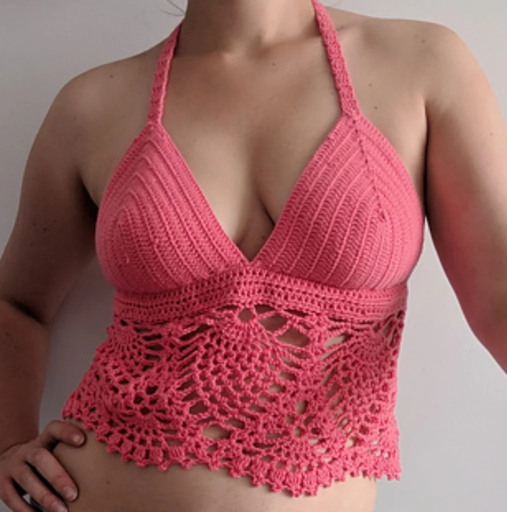 Person wearing a pink boho crochet halter top with a solid upper section and an intricate, lacy lower pattern.