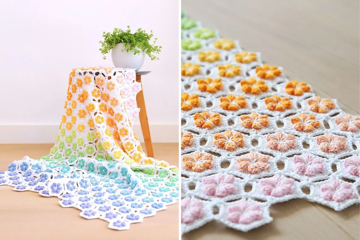 A multicolored crochet blanket with a flower pattern is draped over a wooden stool next to a white plant pot; close-up shows pink, yellow, and orange flower details.
