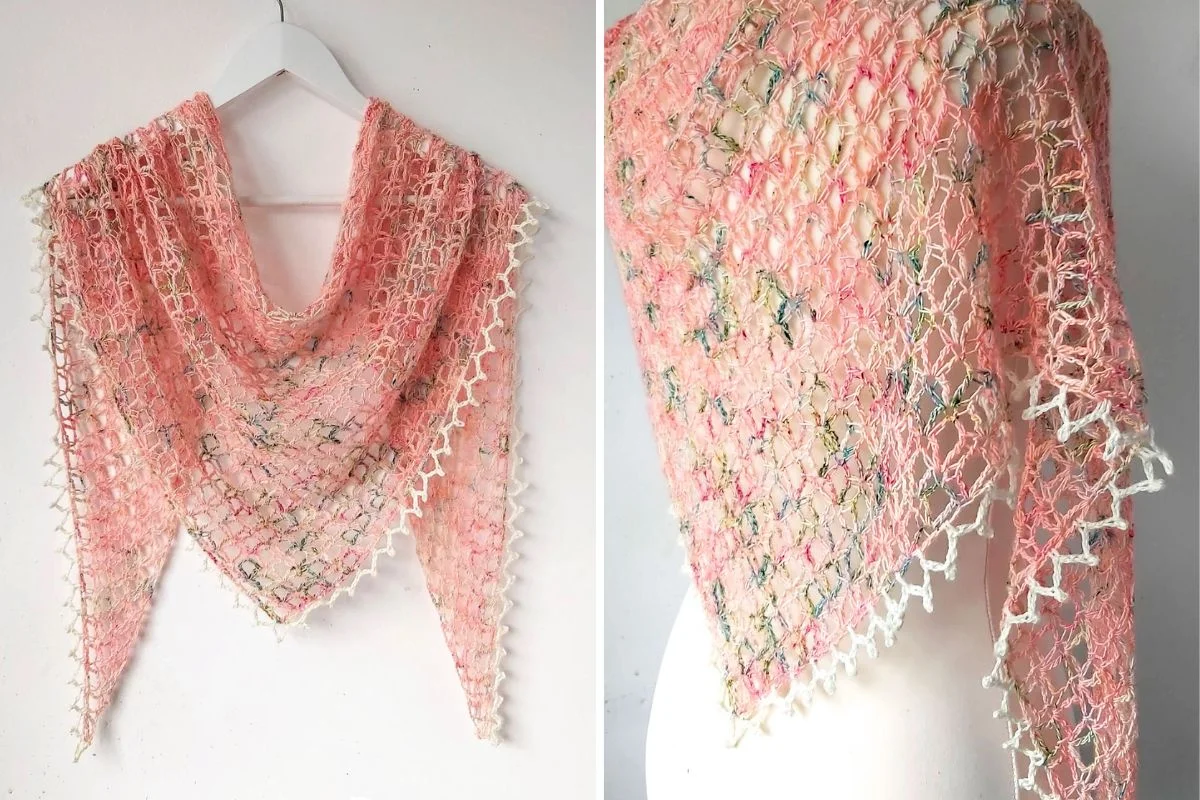 A light pink, lacy triangular shawl with a white crochet edge is displayed on a hanger and draped over a mannequin.
