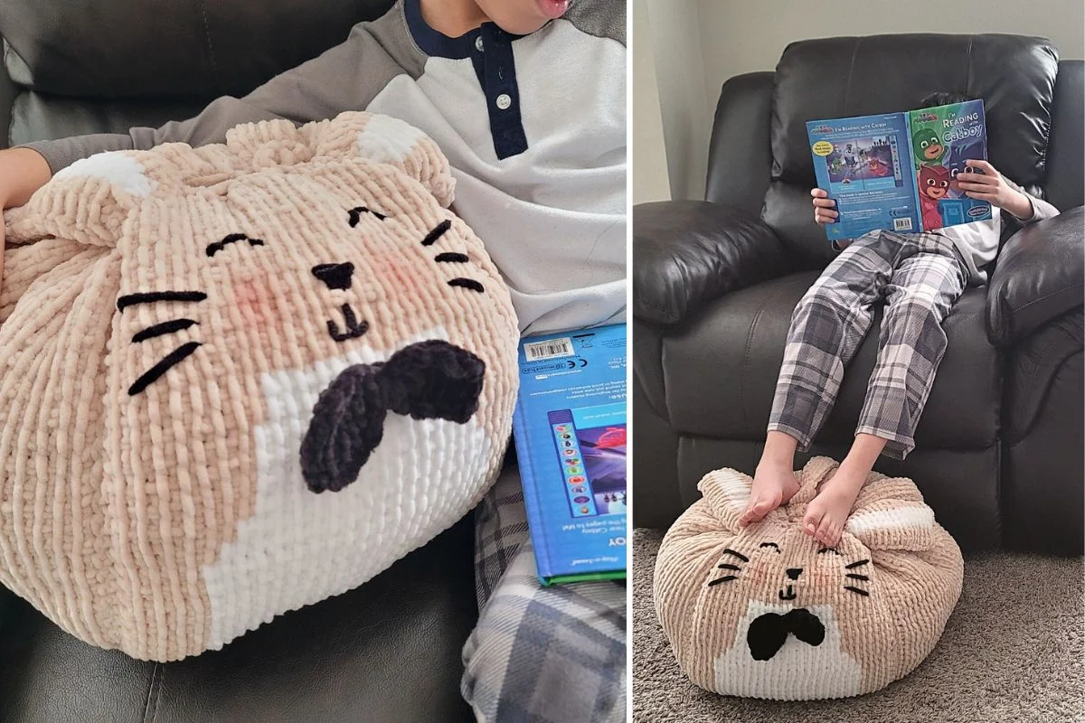 A child sitting on a couch with a book, feet resting on a plush, round Mister Floppy Pouf—a cat pillow with a mustache, whiskers, and closed eyes.