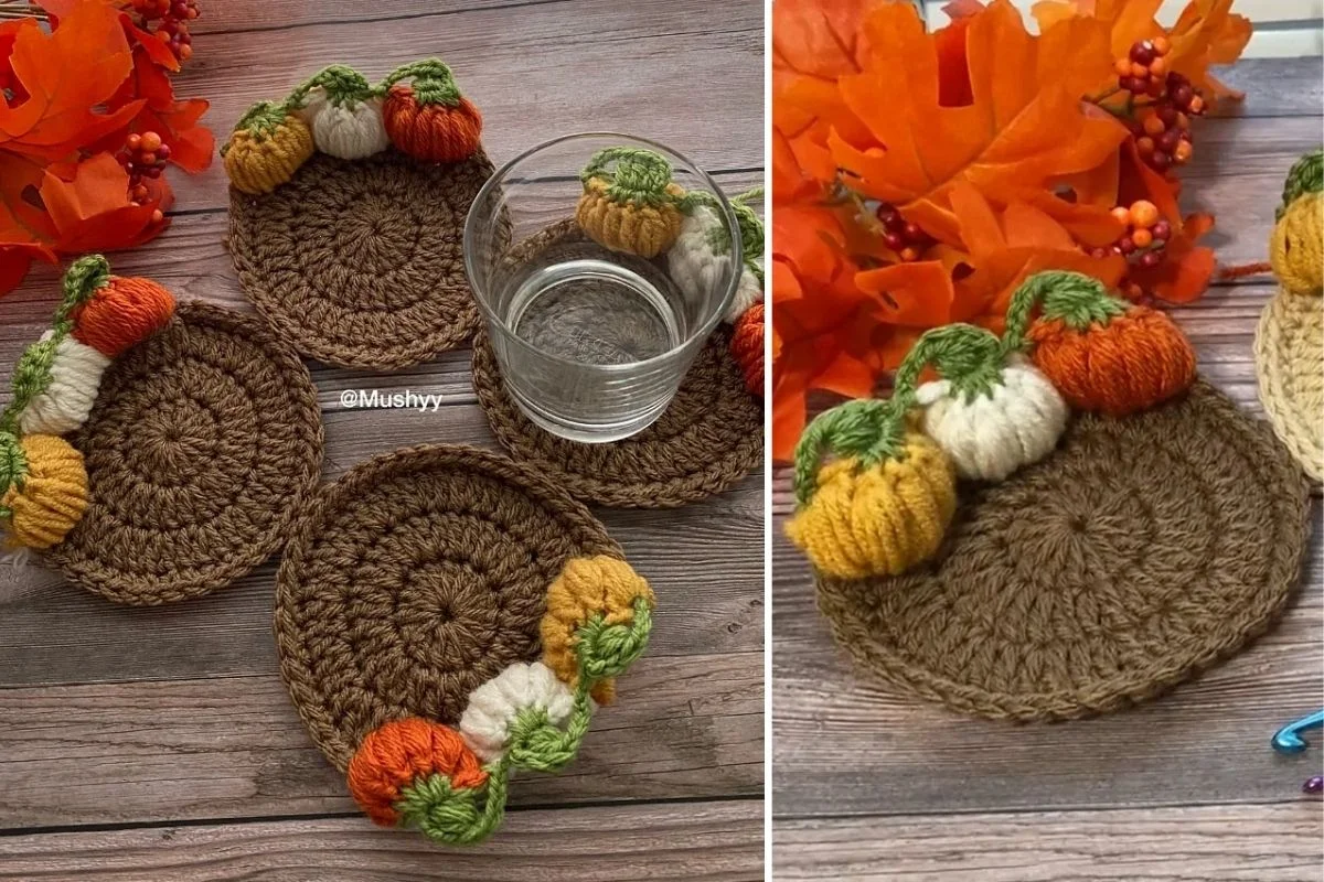 Three round crocheted 3D coasters, each featuring small, colorful pumpkin decorations, are displayed on a wooden surface adorned with autumn leaves and a glass resting on one Pumpkin Coaster.