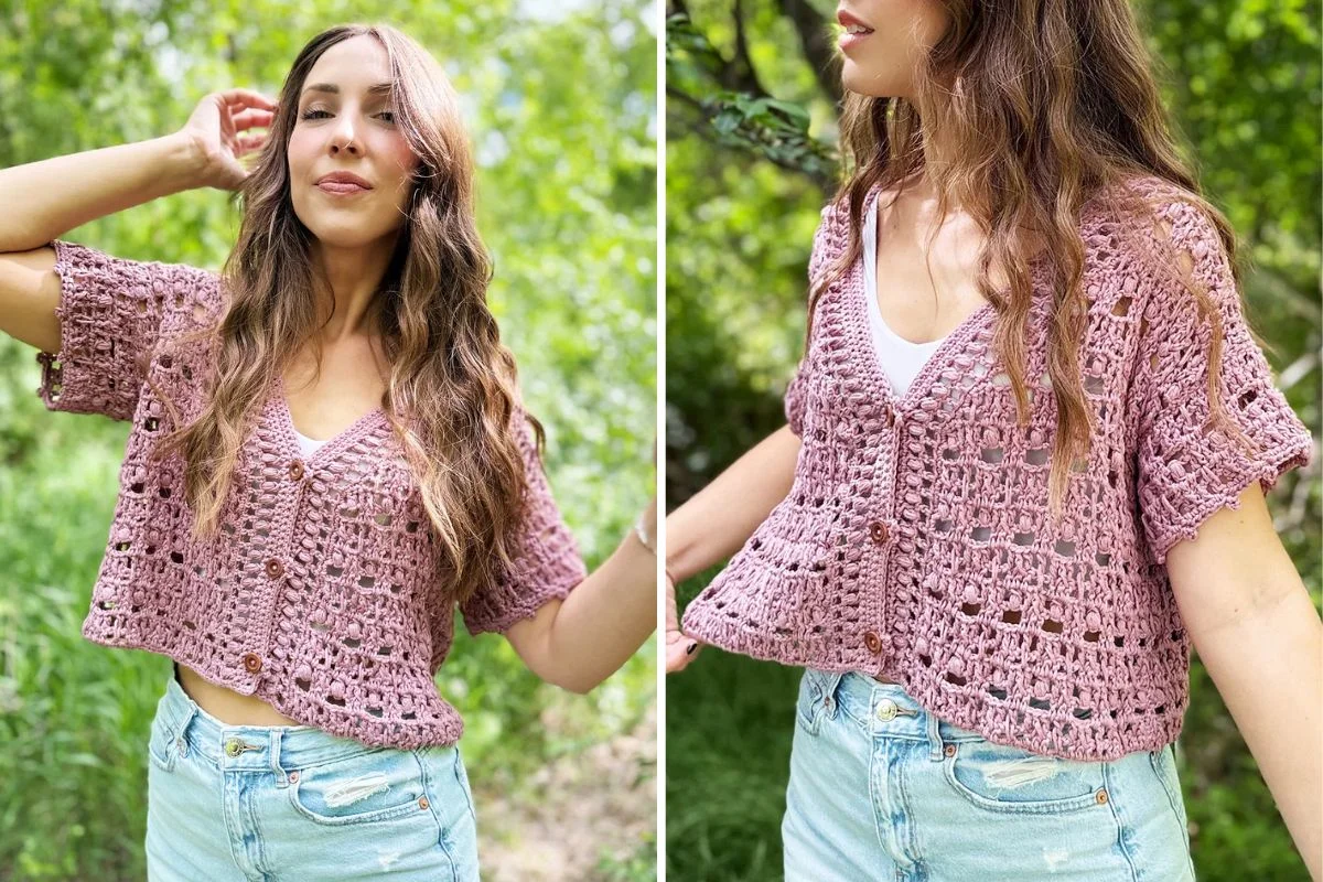 Woman outdoors wearing the Boxy Blooms Cardigan, a pink crocheted short-sleeve piece, over a white top and light blue jeans, with long wavy hair.