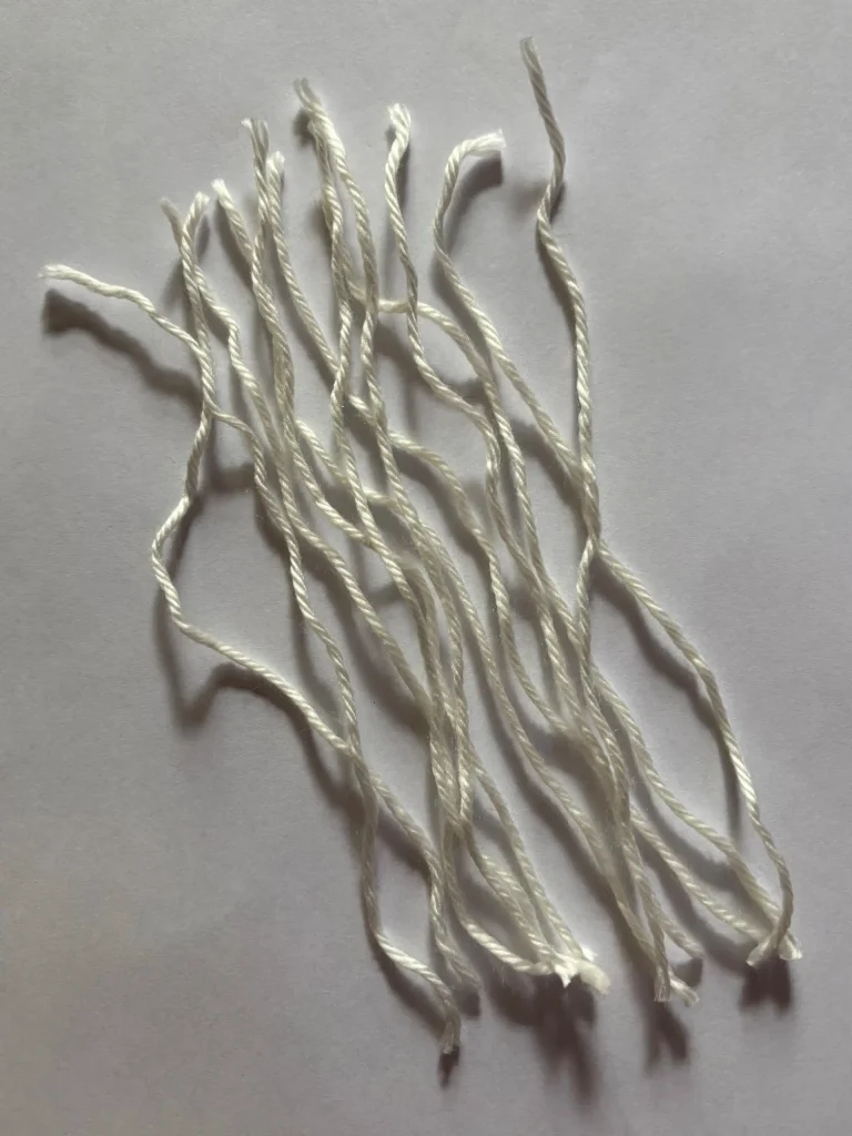Ten pieces of white twisted string are laid out on a flat, light-colored surface, ready to be transformed with a free crochet pumpkin pattern.