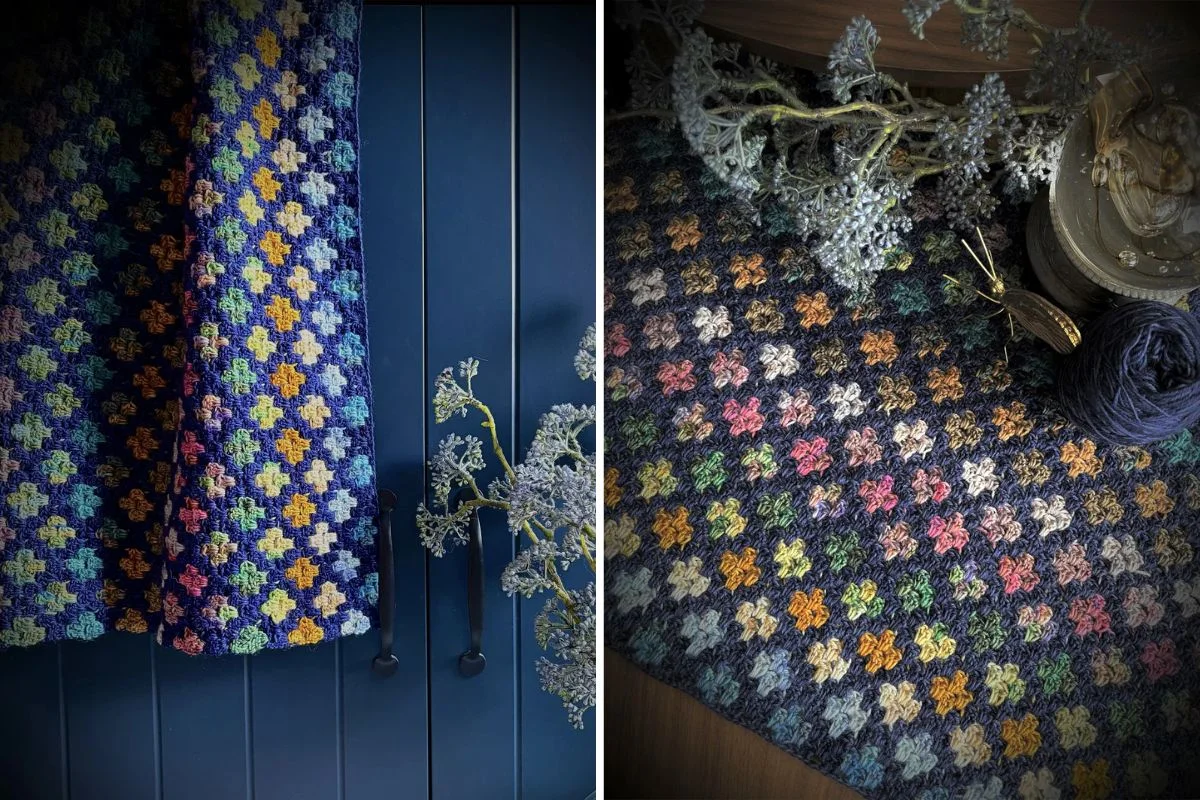 Sanctuary Stripes Blanket: Crocheted blanket with colorful square pattern displayed on a dark surface, with dried flowers and yarn resting nearby.