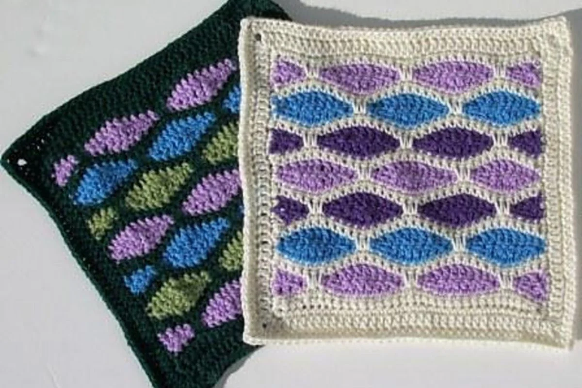 Two crocheted Afghan Square patterns featuring colorful oval motifs in purple, blue, and green shades, reminiscent of stained glass—one finished with a dark green border and the other with a crisp white border.