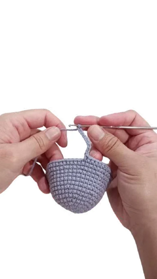 Hands use a crochet hook to work a chain stitch on a partially completed lavender sphere from this free crochet pumpkin pattern.