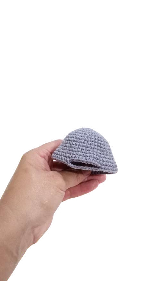 A hand holding a small, gray, dome-shaped crochet pumpkin.