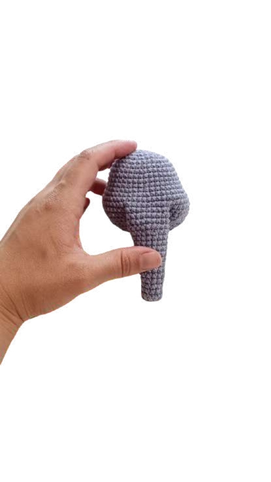 A hand holds the lavender trunk of an elephant amigurumi.