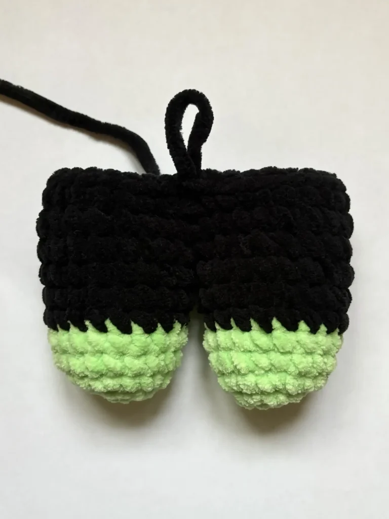 Black and light green crocheted plush pumpkin with a hanging loop.