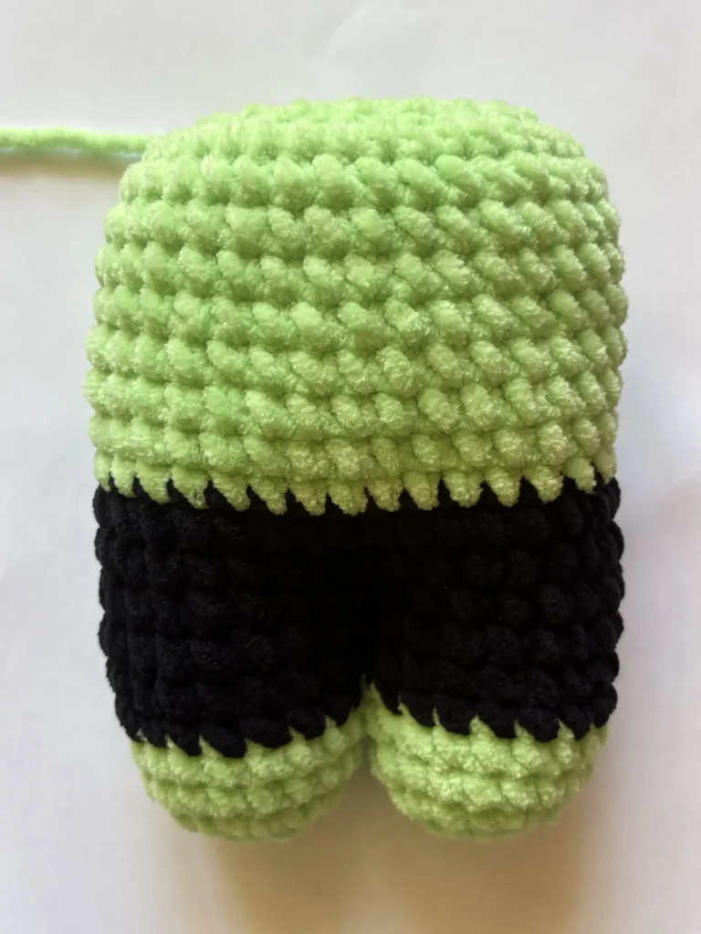 Crocheted Frankenstein plushie made with light green yarn for the upper body and black yarn for the legs.