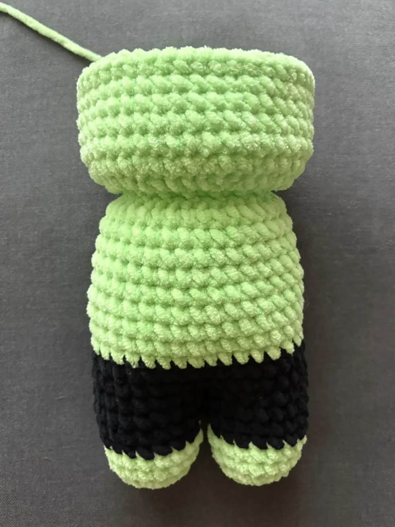 A lime green and black crochet pumpkin plush toy.