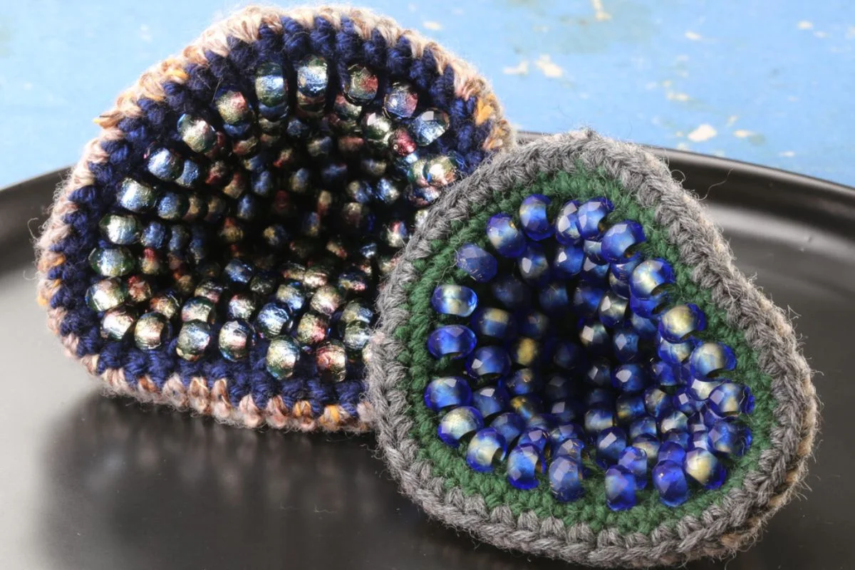 Two handmade crochet bowl-shaped pieces lined with faceted blue and iridescent beads.