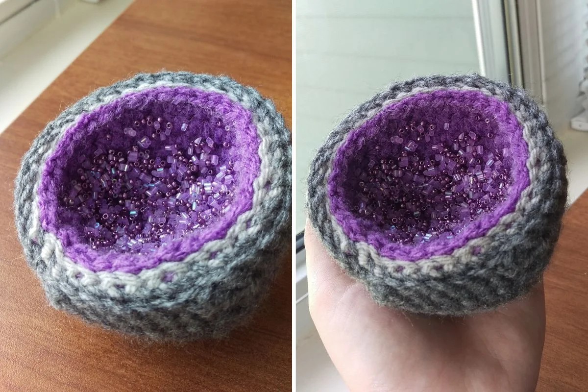 A small, crocheted bowl with a gray exterior and purple interior, filled with purple seed beads like a geode.