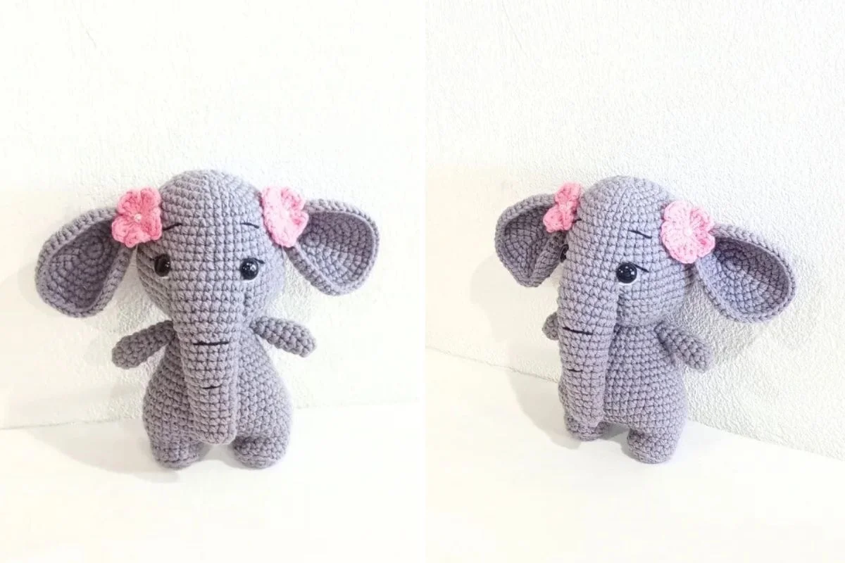 Cute crocheted grey elephant stuffed animal with pink flowers on its ears, shown from the front and side.