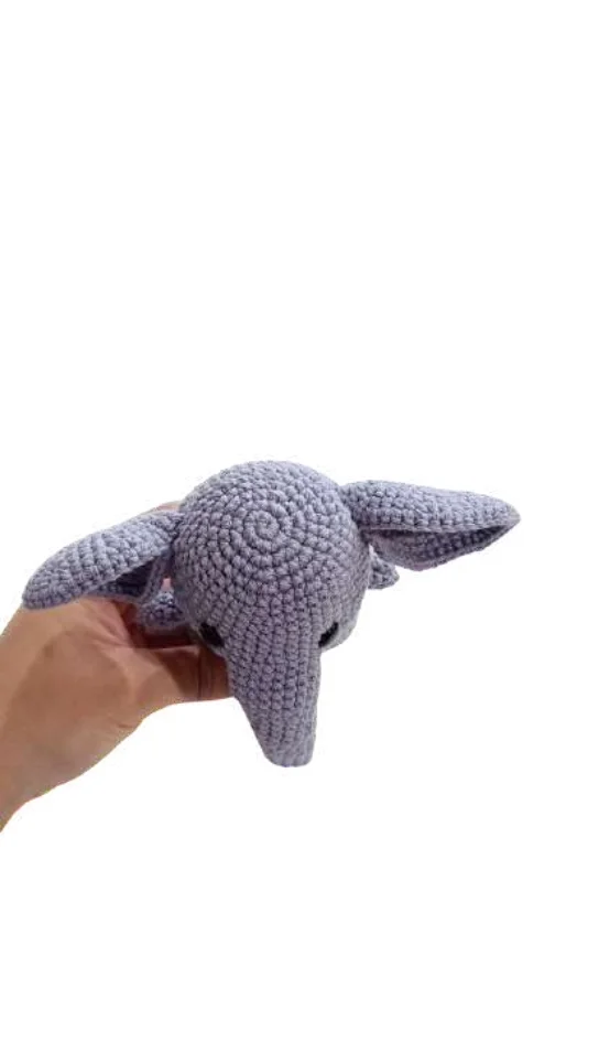 A hand holding a gray elephant amigurumi.