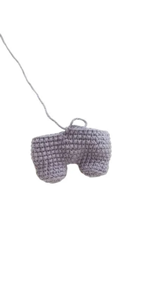 A lavender-colored crochet pumpkin pattern piece with an attached yarn tail.