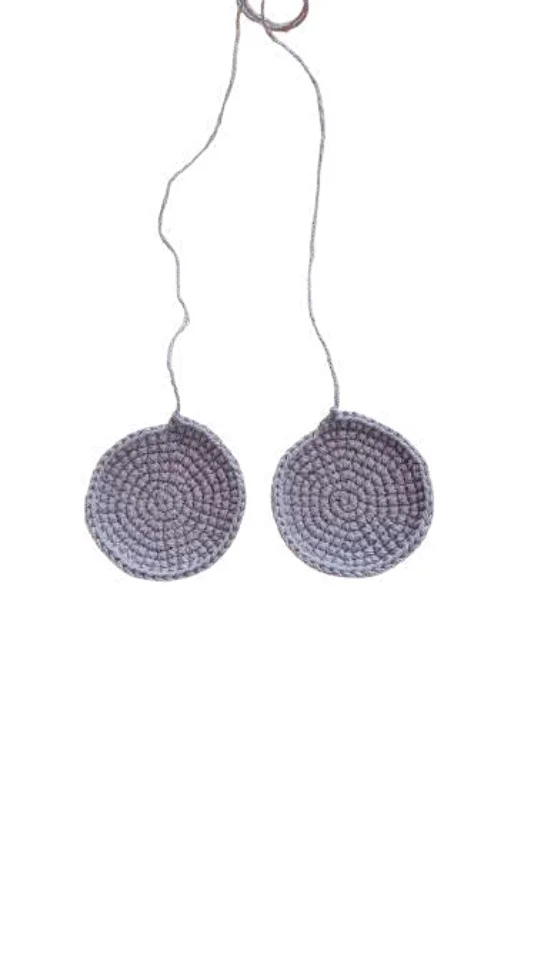 Two circular, light purple crocheted pieces for an elephant amigurumi, connected by a single thread.