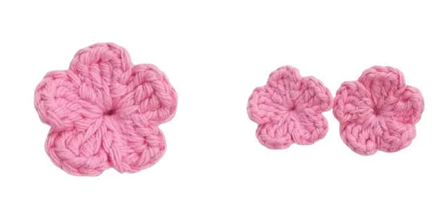Three pink crocheted flowers displayed alongside an elephant amigurumi.