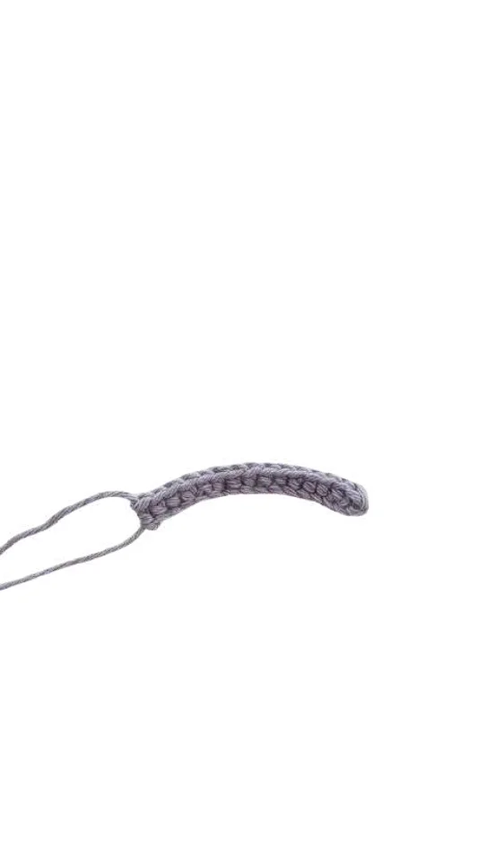 A short row of grey crochet stitches, as seen in a crochet pumpkin pattern, with a tail of yarn hanging from one end.