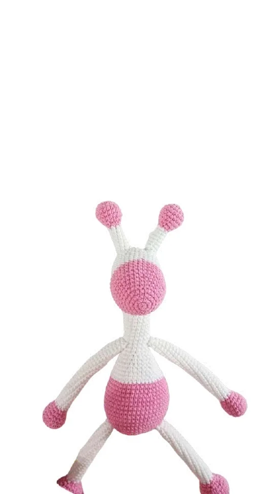 A white and pink crocheted alien with four limbs and two antennae, crafted using techniques similar to a crochet pumpkin pattern.