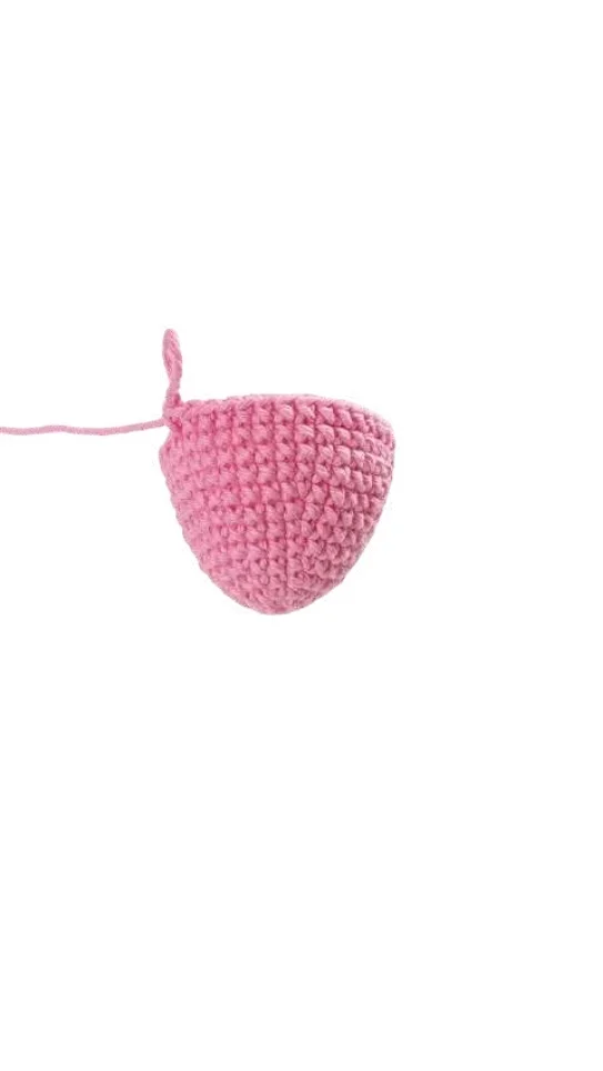 A small, pink, cone-shaped piece of crochet pumpkin pattern work with a single strand of yarn attached.
