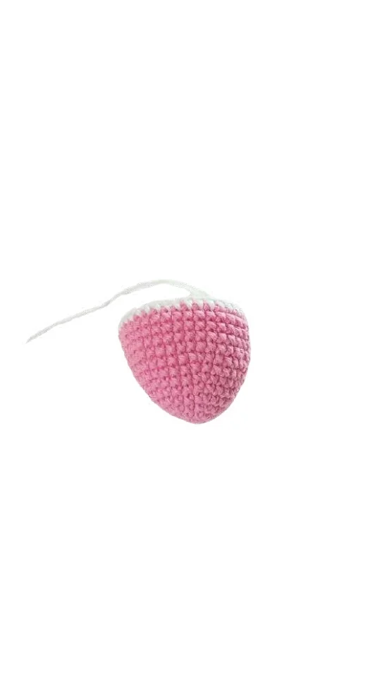 A pink crocheted strawberry toy with a white top and a short white string, crafted in a style similar to a giraffe amigurumi.