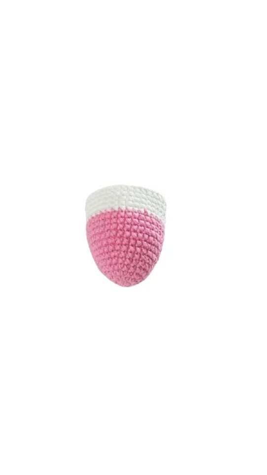 A small, cone-shaped object crocheted with pink yarn on the bottom and white yarn on the top rim, perfect for a free crochet pumpkin pattern.