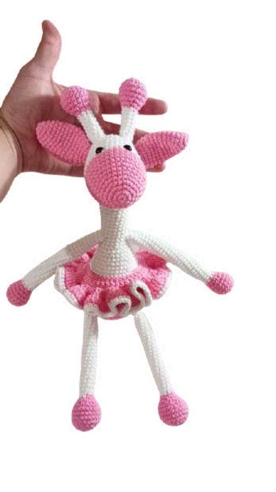 A hand holding a crocheted giraffe amigurumi wearing a pink tutu.