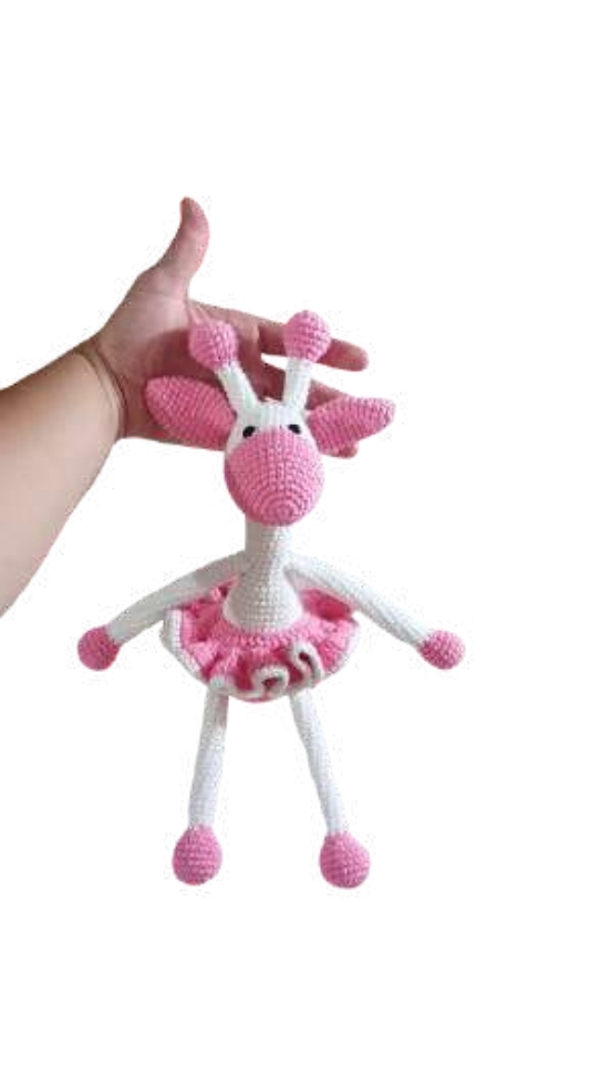 A hand holding a crocheted toy giraffe wearing a pink tutu, styled like a crochet pumpkin pattern.
