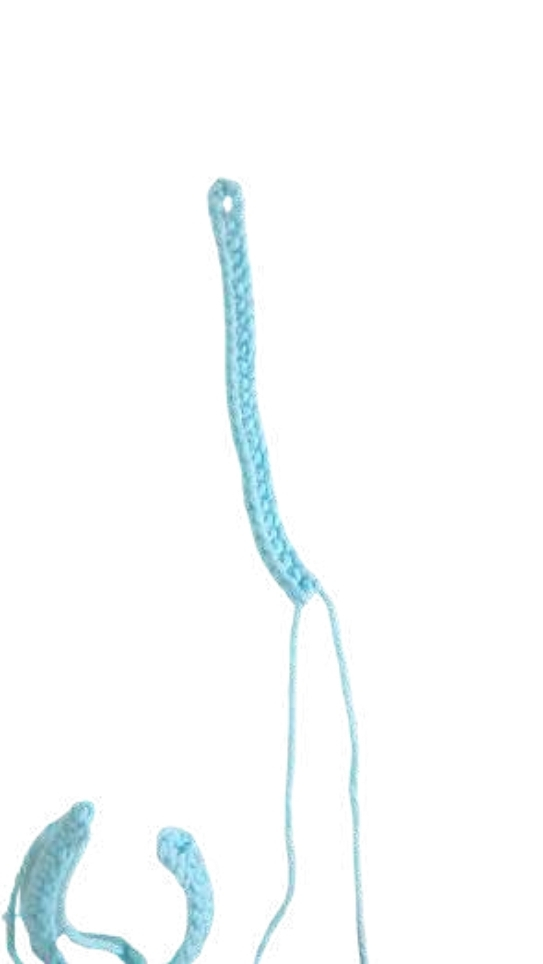 A strip of light blue crochet work, similar to a base for a pumpkin crochet pattern, with two loose yarn tails at the end.