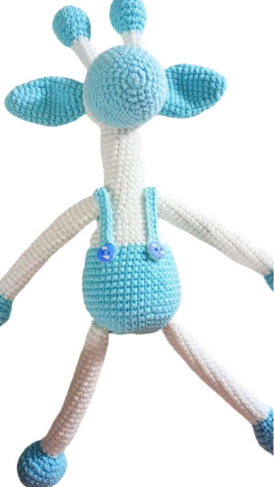 Crochet giraffe amigurumi in white and light blue wearing overalls with blue buttons.